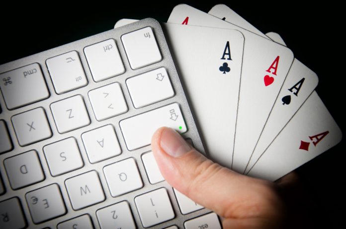 Poker On-line. Keyboard and four aces in hand.