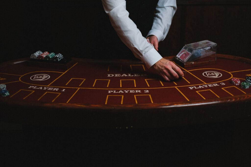 Dealer handling cards at a casino card table with chip stacks